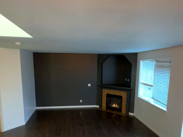 Charcoal gray accent wall and fireplace in a residential interior painting project by Blissful Painting LLC