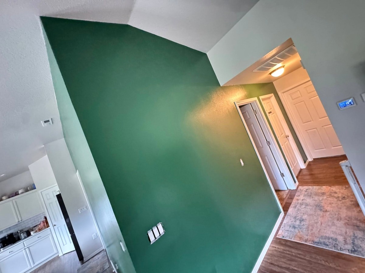 Deep green interior accent wall with white trim in a residential living space.