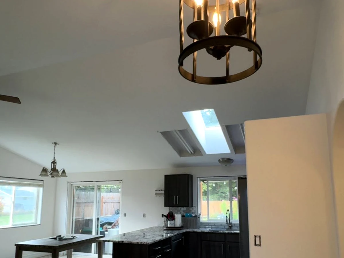 Bright open-concept kitchen and living area with freshly painted interior walls and vaulted ceiling.