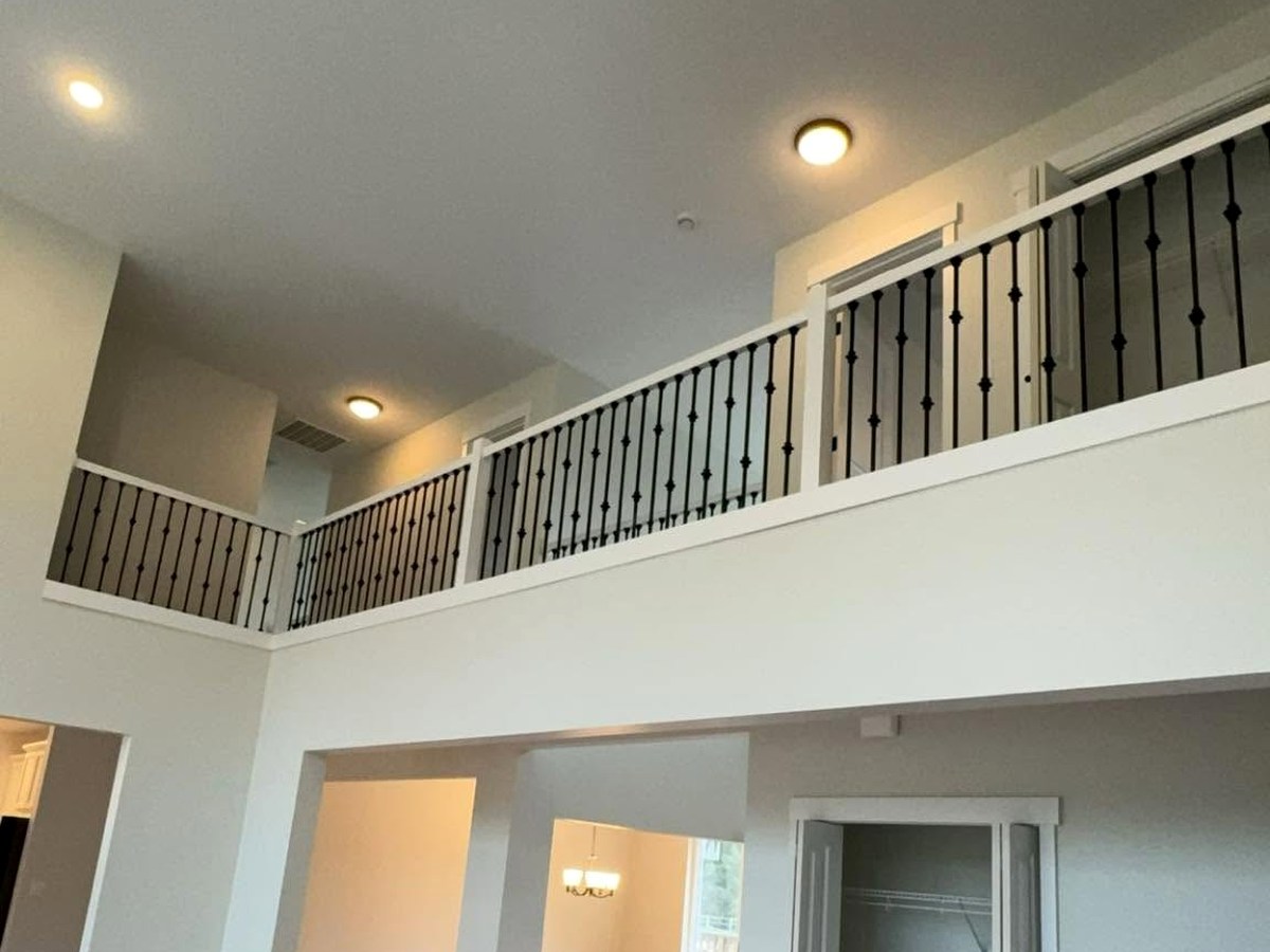 Freshly painted two-story home interior with light walls, white trim, and black staircase railings.