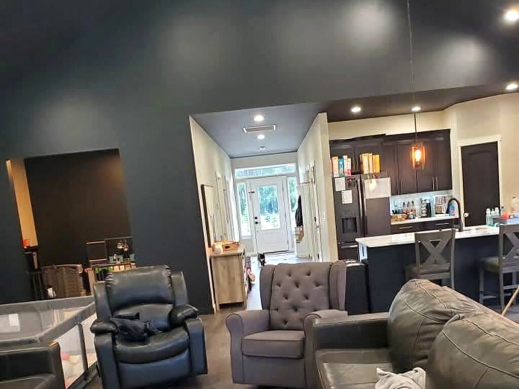 Interior painting project featuring dark painted walls, white trim, and an open living area.